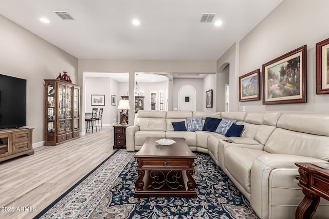 living area featuring arched walkways, visible vents, wood finished floors, and recessed lighting