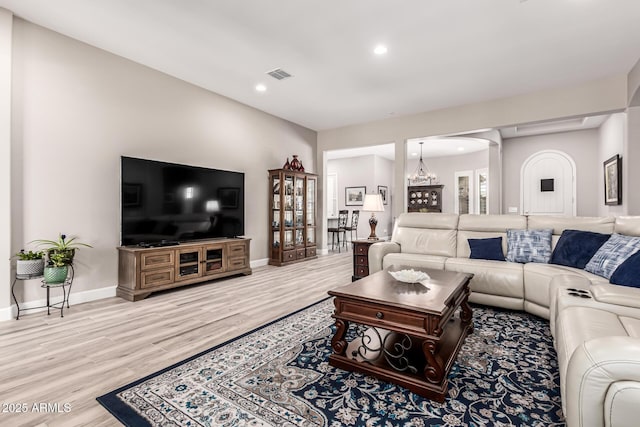 living room with visible vents, arched walkways, light wood-style floors, and baseboards