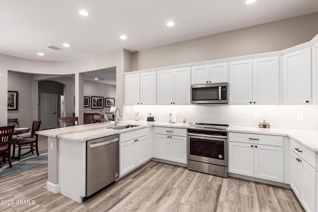 kitchen featuring backsplash, visible vents, appliances with stainless steel finishes, arched walkways, and a sink