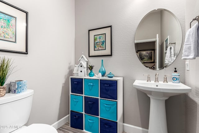 bathroom with a sink, baseboards, toilet, and wood finished floors