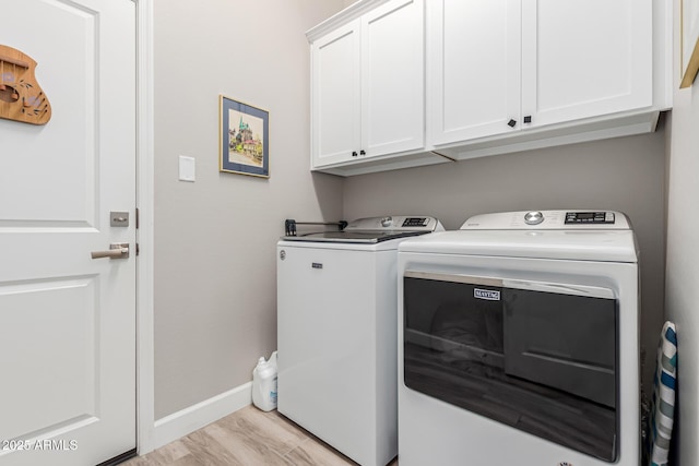 clothes washing area featuring separate washer and dryer, cabinet space, and baseboards