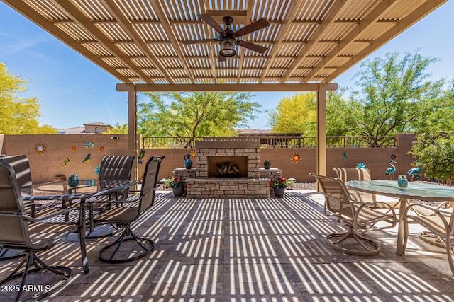view of patio with fence, outdoor dining space, ceiling fan, and an outdoor stone fireplace