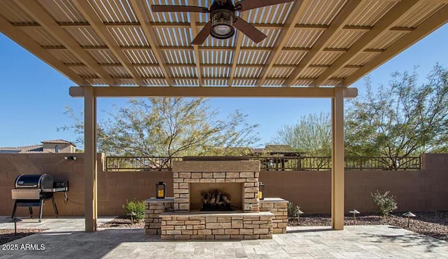view of patio / terrace featuring area for grilling, an outdoor stone fireplace, fence, and a ceiling fan