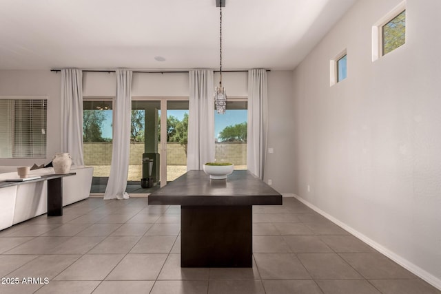 unfurnished dining area with baseboards and tile patterned flooring
