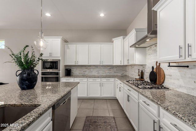 kitchen featuring wall chimney range hood, tasteful backsplash, white cabinets, and appliances with stainless steel finishes