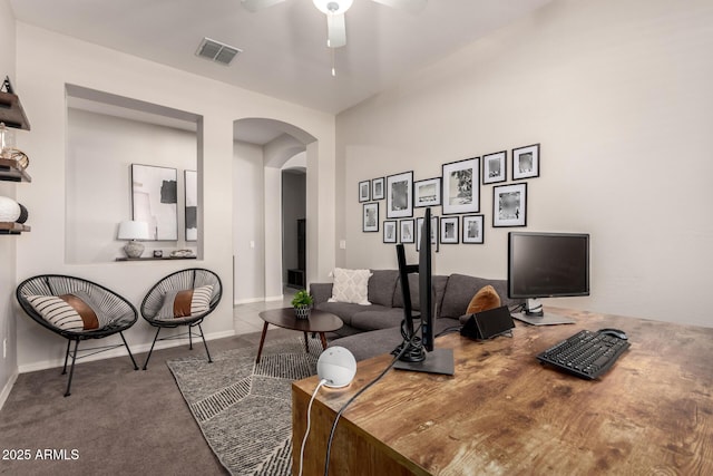 office space featuring baseboards, visible vents, ceiling fan, arched walkways, and carpet