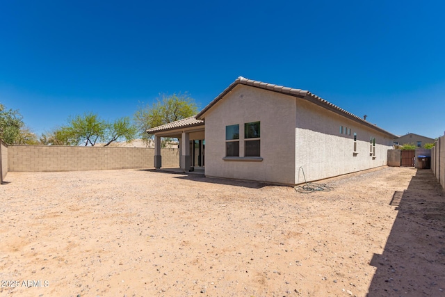 back of house featuring stucco siding, a fenced backyard, and a tile roof