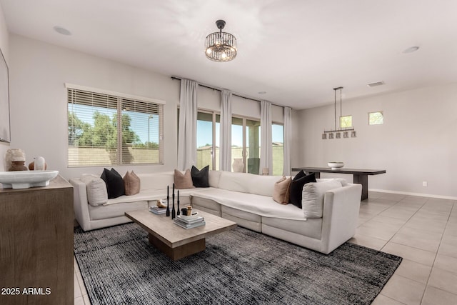living room with light tile patterned floors, visible vents, baseboards, and an inviting chandelier