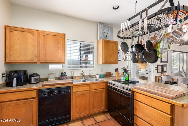 kitchen featuring sink, light tile patterned floors, and black appliances