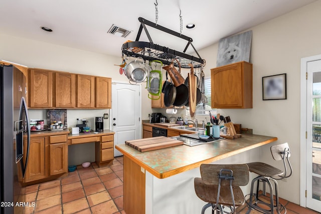 kitchen with stainless steel fridge, a kitchen breakfast bar, kitchen peninsula, dishwasher, and a wealth of natural light