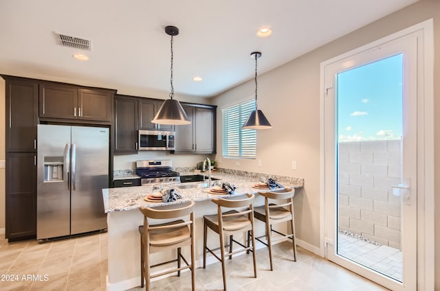 kitchen with decorative light fixtures, a wealth of natural light, kitchen peninsula, and appliances with stainless steel finishes