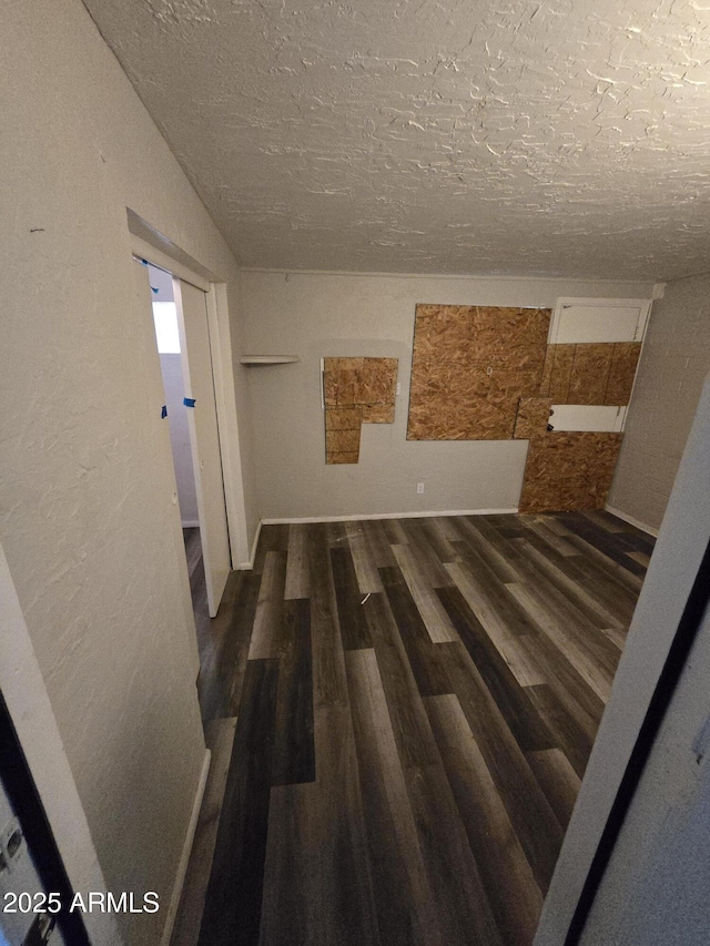 hall with a textured ceiling and wood finished floors