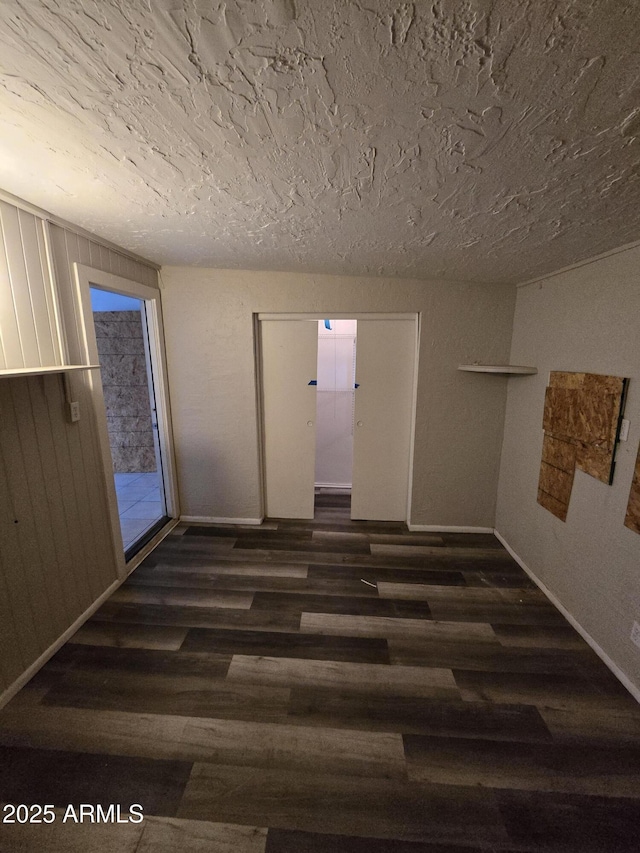 spare room featuring a textured ceiling, baseboards, and wood finished floors