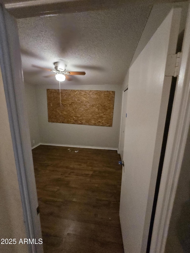 spare room with ceiling fan, baseboards, a textured ceiling, and wood finished floors