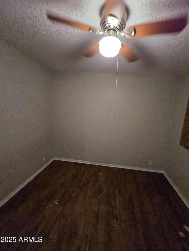 empty room featuring dark wood-style floors, ceiling fan, a textured ceiling, and baseboards