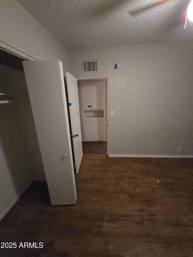 interior space with visible vents, a textured ceiling, baseboards, and wood finished floors