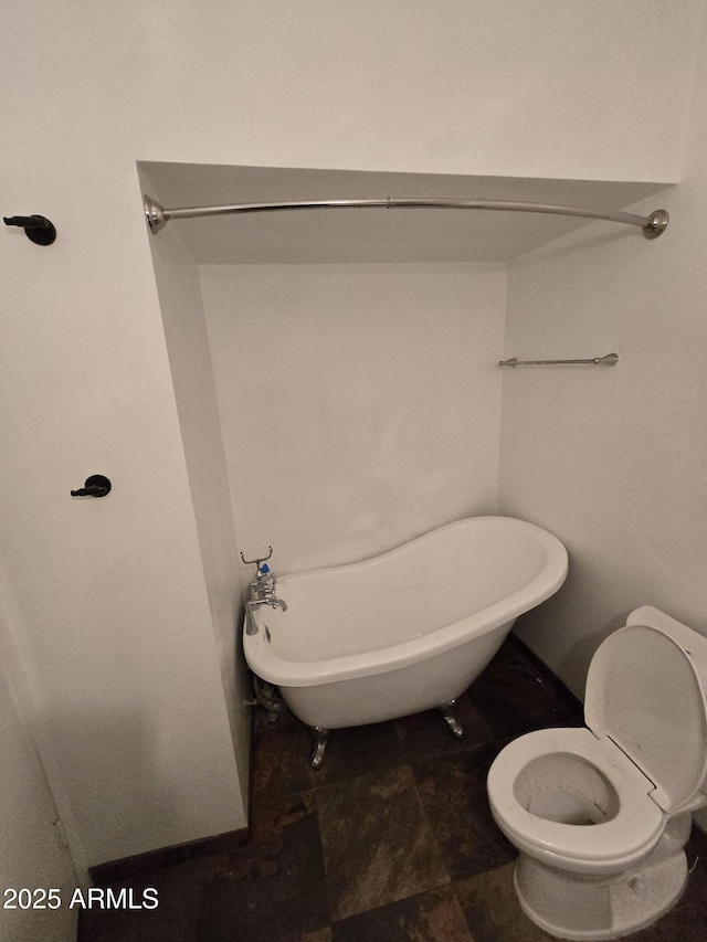 bathroom featuring a soaking tub and toilet