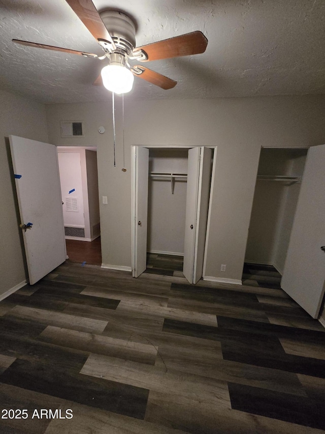 bedroom featuring multiple closets, visible vents, a textured ceiling, wood finished floors, and baseboards