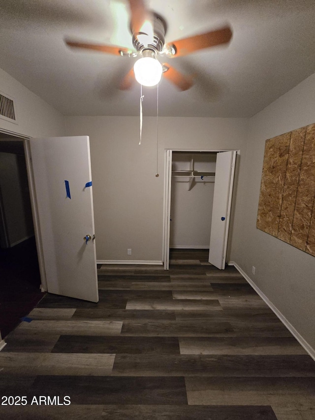 unfurnished bedroom featuring baseboards, visible vents, dark wood-style floors, ceiling fan, and a closet