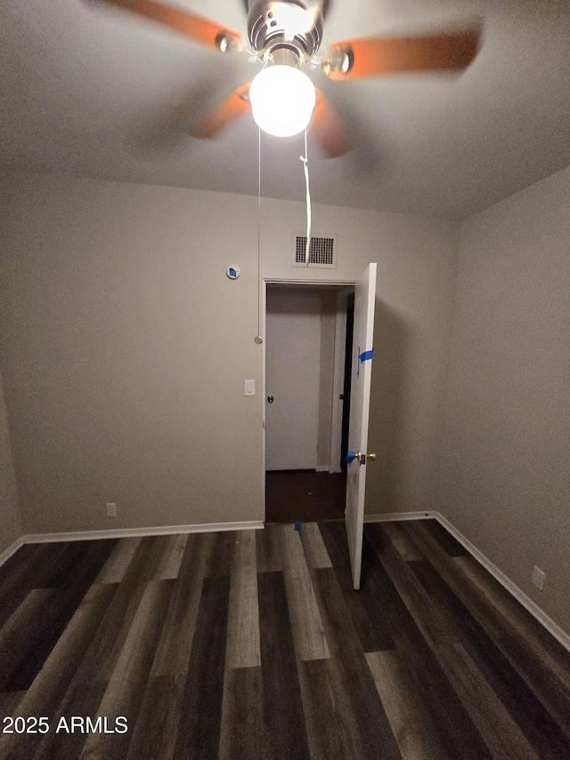 unfurnished room featuring baseboards, visible vents, and wood finished floors