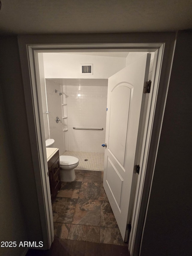 full bathroom with toilet, vanity, a stall shower, visible vents, and stone finish floor