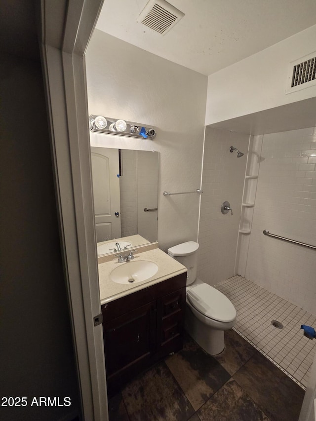 full bath with tiled shower, toilet, visible vents, and vanity