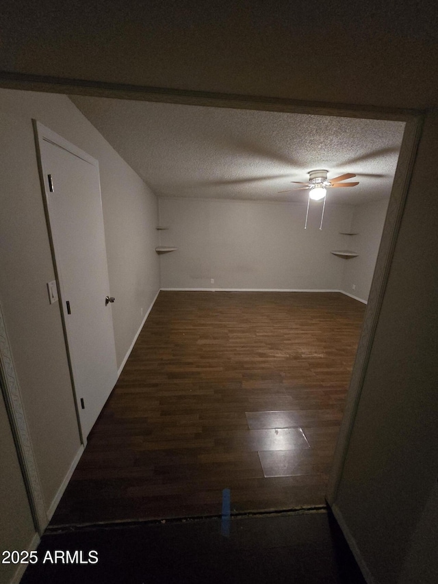 unfurnished room with a textured ceiling, ceiling fan, wood finished floors, and baseboards