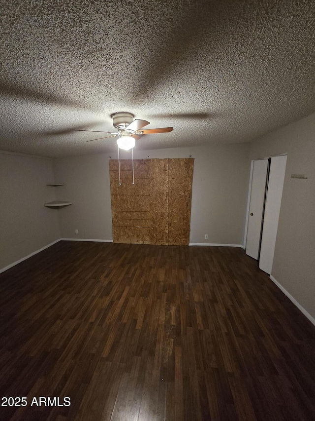 spare room featuring dark wood finished floors, a textured ceiling, baseboards, and ceiling fan