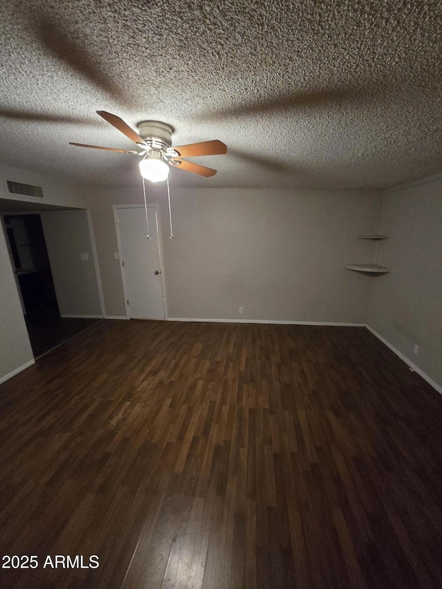 empty room with ceiling fan, a textured ceiling, visible vents, baseboards, and dark wood-style floors