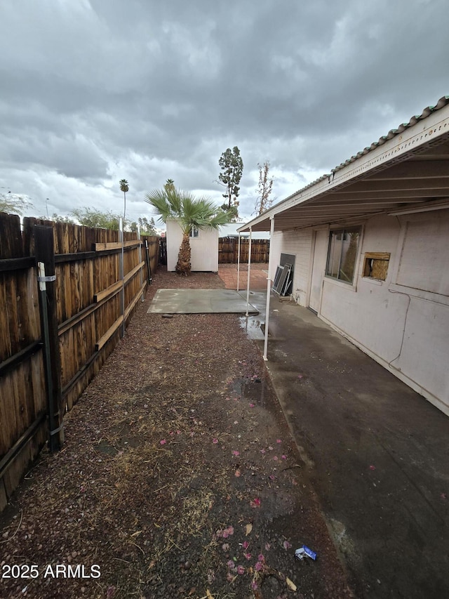 view of yard with a storage shed, a fenced backyard, an outbuilding, and a patio