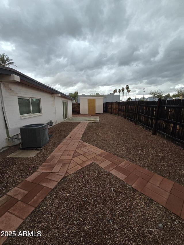 view of yard with a patio, a fenced backyard, a storage unit, an outdoor structure, and central air condition unit