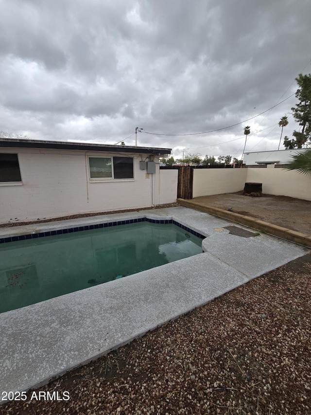 pool with a patio area and fence