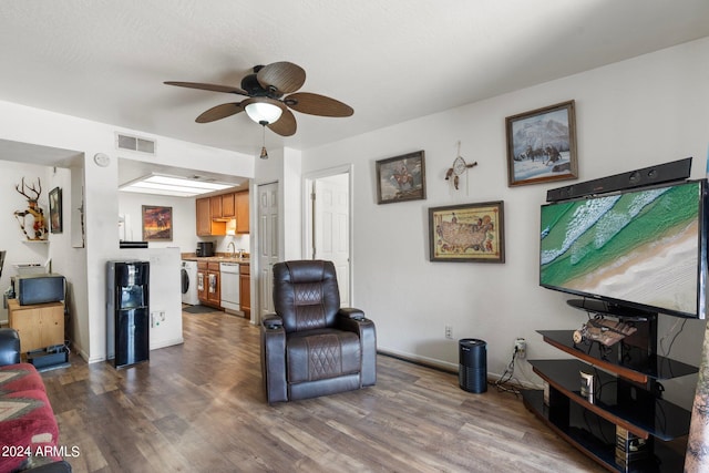 living room with washer / dryer, dark wood-type flooring, and ceiling fan