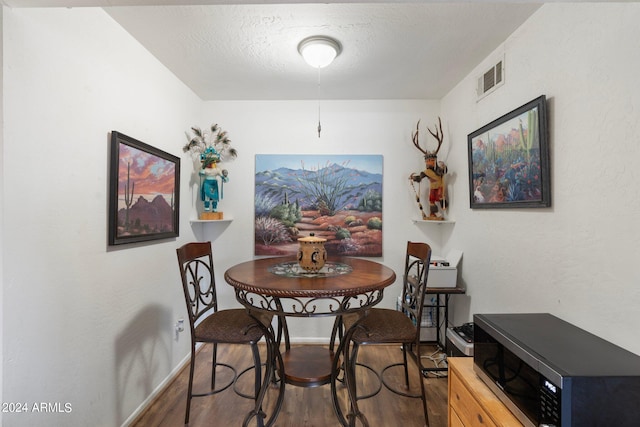 dining space with a textured ceiling and dark wood-type flooring