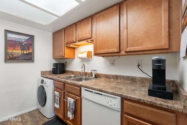 kitchen with dark stone countertops, dishwasher, washer / dryer, hardwood / wood-style floors, and sink