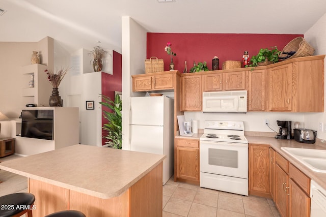 kitchen with a center island, sink, white appliances, a breakfast bar area, and light tile patterned floors