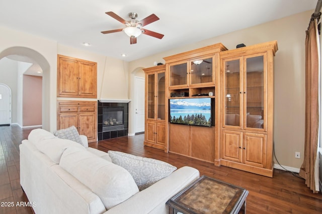 9305 E Canyon View Rd, Scottsdale, AZ 85255 - living room with dark wood-type flooring, a tile fireplace, arched walkways, and ceiling fan