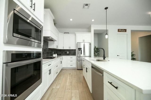 kitchen featuring tasteful backsplash, visible vents, custom range hood, stainless steel appliances, and a sink