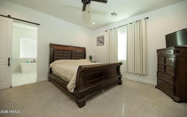 bedroom with visible vents, ceiling fan, light colored carpet, a barn door, and ensuite bath