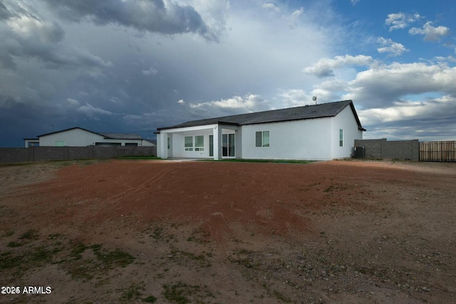 rear view of house featuring fence and central AC