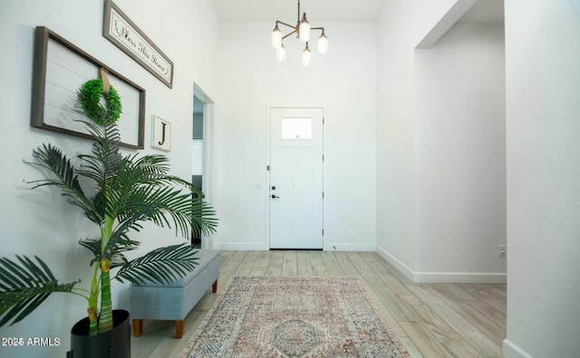 foyer featuring a chandelier, baseboards, and wood finished floors