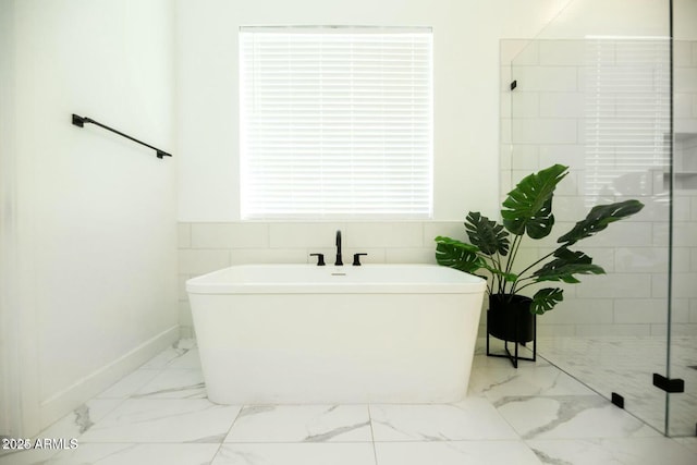 bathroom featuring a tile shower, a soaking tub, marble finish floor, and baseboards