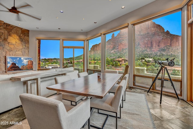 sunroom / solarium featuring a mountain view, stone tile flooring, and recessed lighting