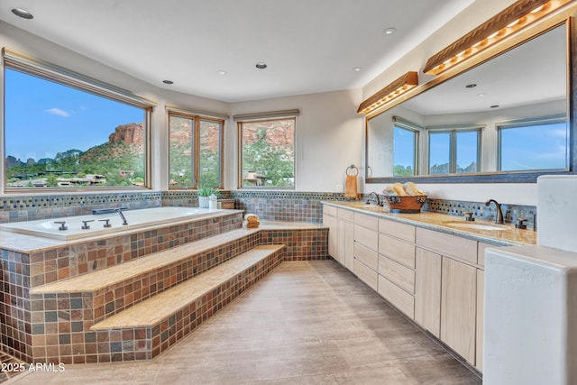 full bathroom featuring a sink, double vanity, recessed lighting, and a garden tub