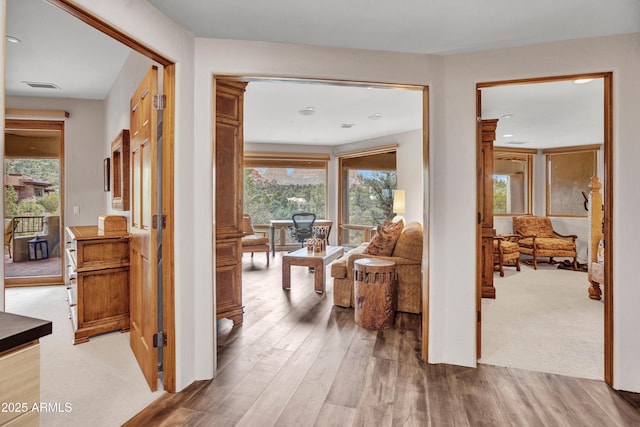 hallway with visible vents, a wealth of natural light, and wood finished floors