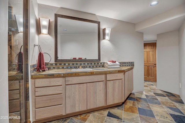 bathroom with a shower with door, tasteful backsplash, vanity, recessed lighting, and stone finish flooring