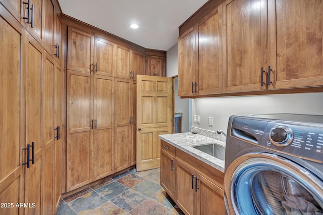 washroom featuring stone finish floor, recessed lighting, a sink, washer / dryer, and cabinet space