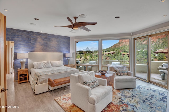 bedroom with a mountain view, access to exterior, recessed lighting, and light wood-style floors