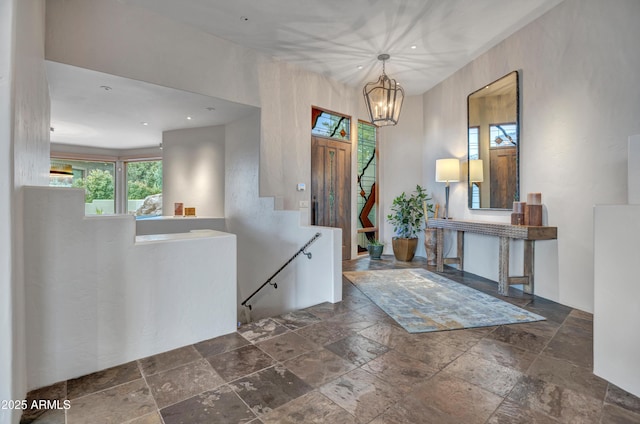 entrance foyer with recessed lighting, stone tile floors, and an inviting chandelier