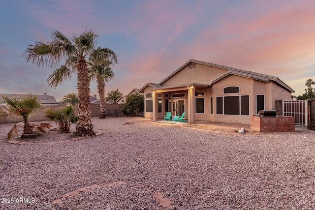 back house at dusk featuring a patio area